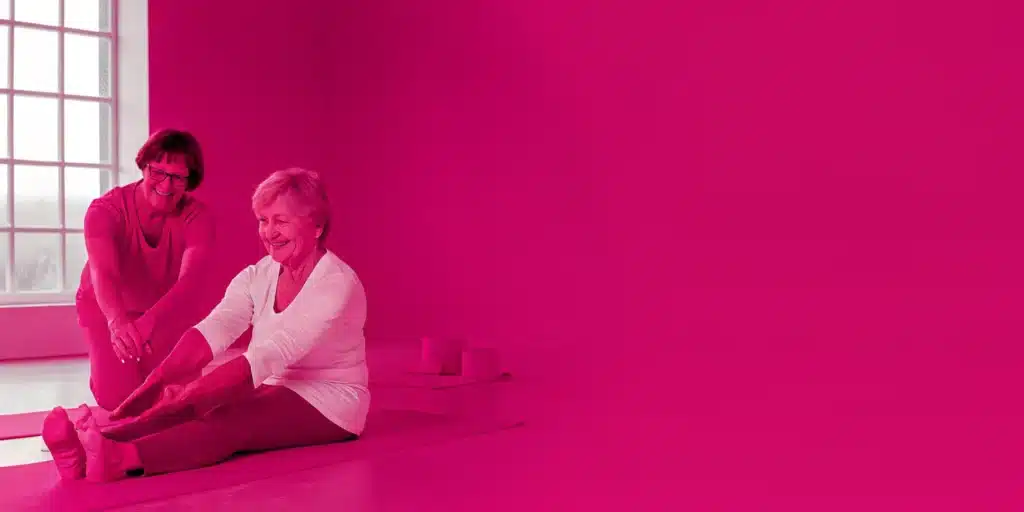 Two seniors practice gentle stretching on yoga mats for improved flexibility and balance.