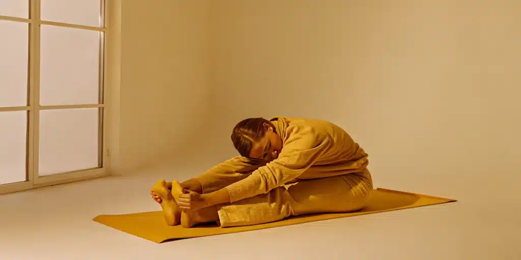 A beginner doing a seated forward fold mobility exercise.