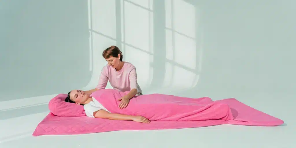 A client receives one on one assisted stretching from a professional on a therapy mat.