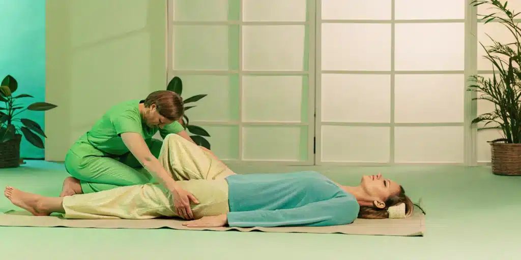 A physical therapist assists a woman with a leg stretch to improve her range of motion.